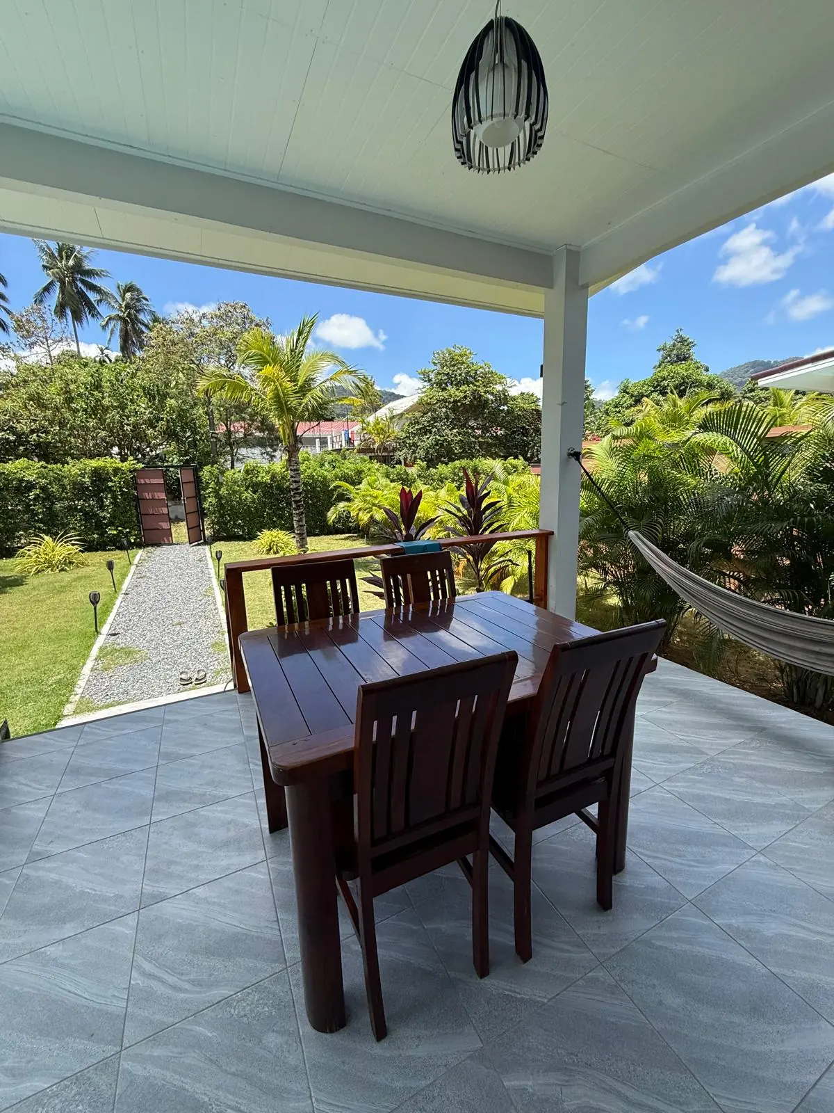 Covered dining terrace and tropical garden at the Baan Tai villa